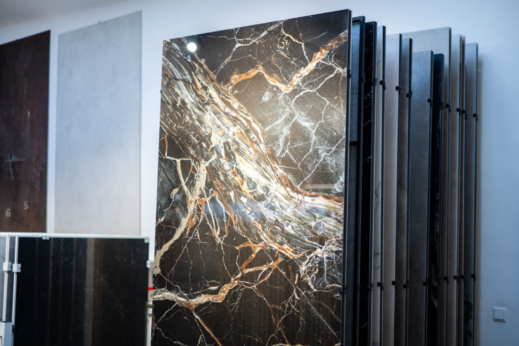 Großformatige Marmoroptik-Fliese mit goldenen Adern im Schauraum von MABELA Fliesen und Handels GmbH – elegante Designfliesen für Bad und Wohnbereich.