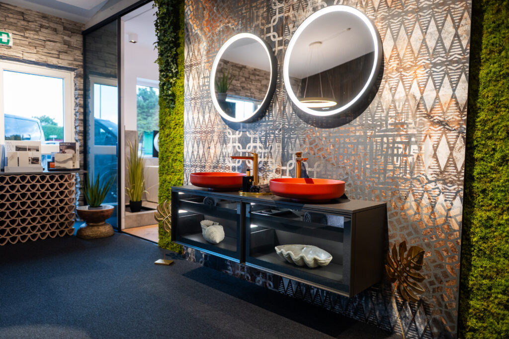 Modernes Doppelwaschbecken mit roten Aufsatzbecken und LED-Spiegeln bei MABELA Fliesen und Handels GmbH – kreative Badgestaltung im Schauraum.