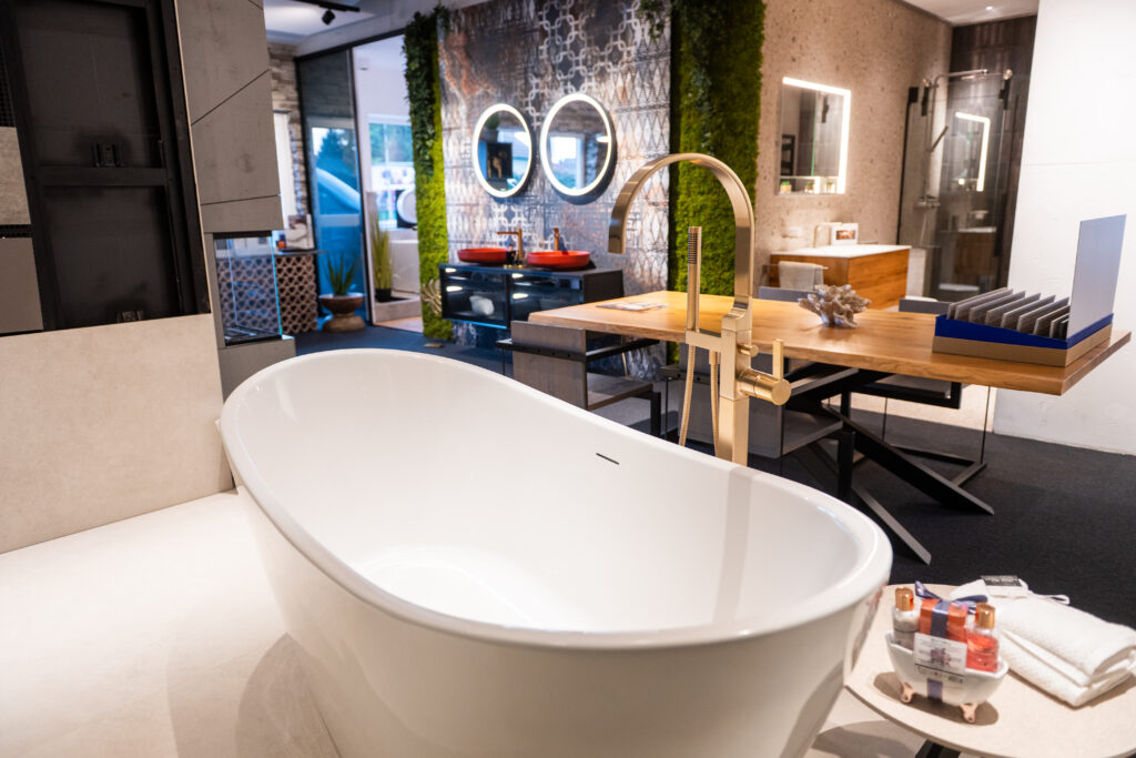 Freistehende Design-Badewanne mit goldener Armatur im Schauraum von MABELA Fliesen und Handels GmbH – exklusive Bad- und Fliesengestaltung.